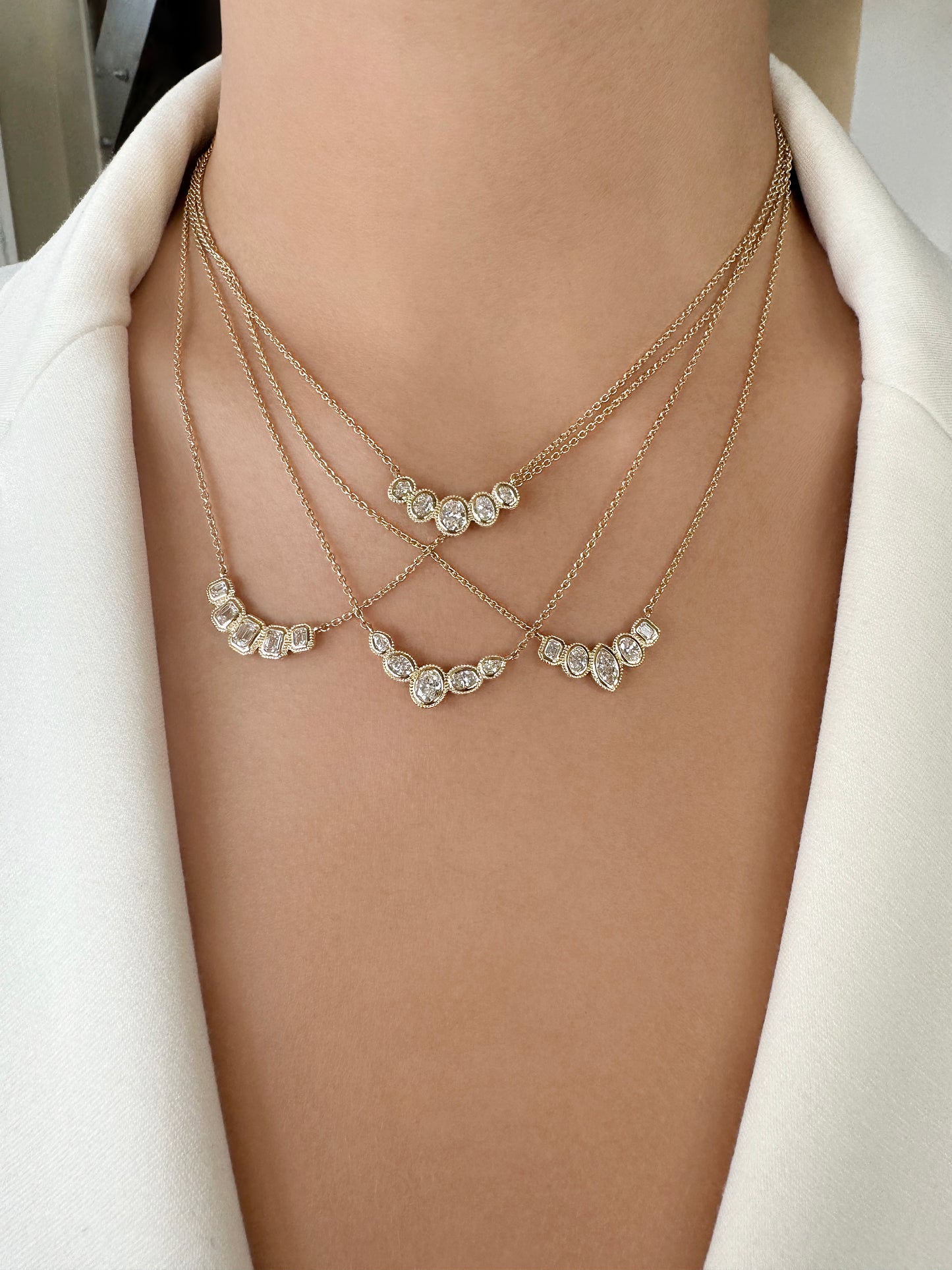 Sig Ward Jewelry Lifestyle featuring the Stellar Emerald Cut Diamond Bib Necklace, Stellar Oval Cut Diamond Bib Necklace, Stellar Marquise, Oval and Emerald Cut Diamond Bib Necklace, and Stellar Oval and Pear Shape Diamond Bib Necklace showcasing exquisite diamond craftsmanship in elegant statement necklace designs.