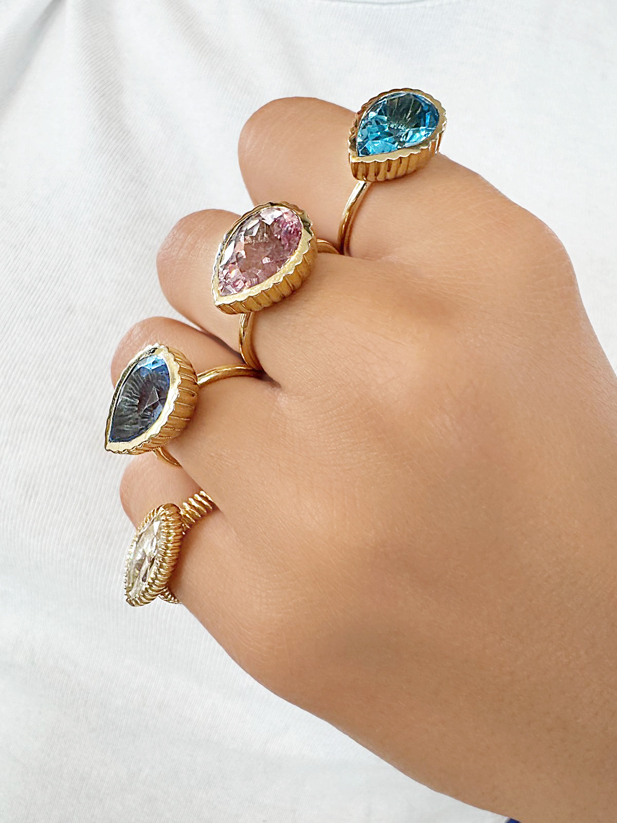 Sig Ward Jewelry 14K yellow gold Omega rings featuring Swiss Topaz, Sapphire, and Ceylon Padparadscha Sapphire gemstones with elegant modern luxury craftsmanship.