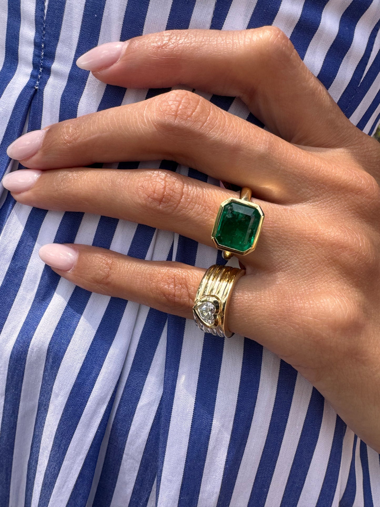 14K yellow gold Romy heart-shaped pinky cigar band paired with an 18K yellow gold Colombian emerald statement ring by Sig Ward Jewelry. 