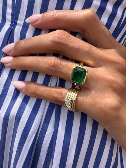 14K yellow gold Romy heart-shaped pinky cigar band paired with an 18K yellow gold Colombian emerald statement ring by Sig Ward Jewelry. 