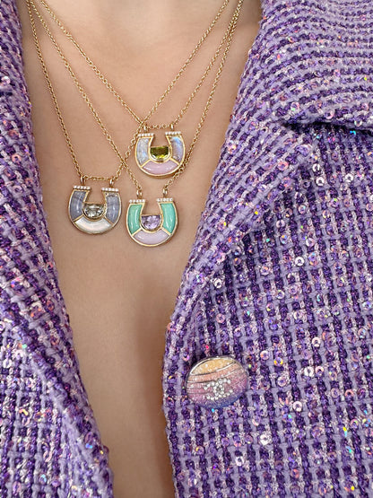 Model wearing layered 14K yellow gold horseshoe pendant necklaces with pastel gemstones, mother-of-pearl, and diamond accents by Sig Ward Jewelry.