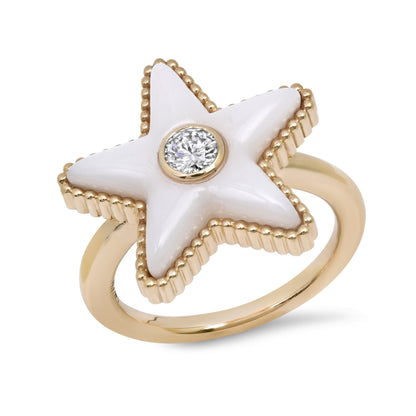 Sig Ward Jewelry Gold ring with a white star-shaped stone and a clear gemstone at its center on a white background